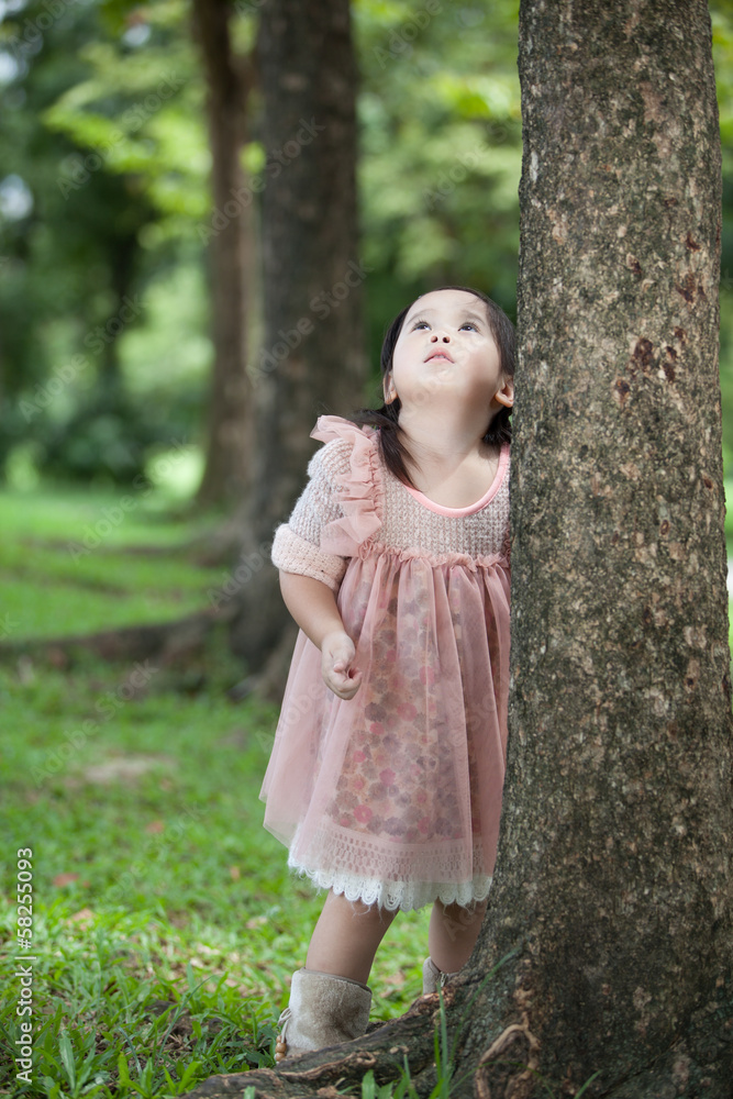 Little girl playing behind the tree