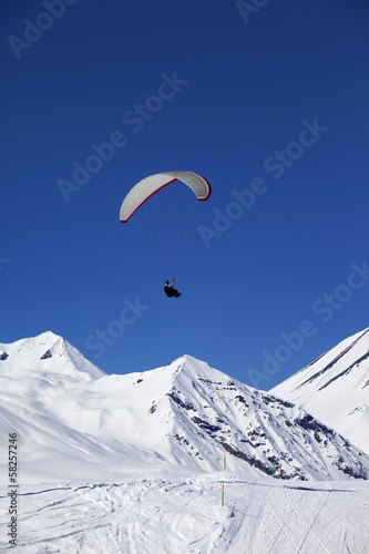 Paraglider in sunny snowy mountains