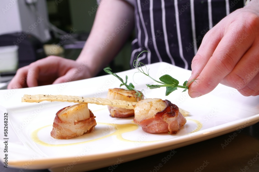 chef plating up plated scallops