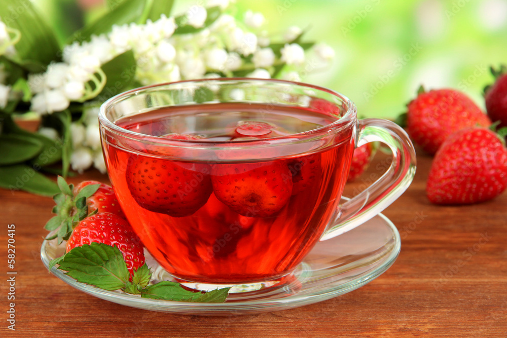 Delicious strawberry tea on table on bright background Delicious strawberry tea on table on bright background