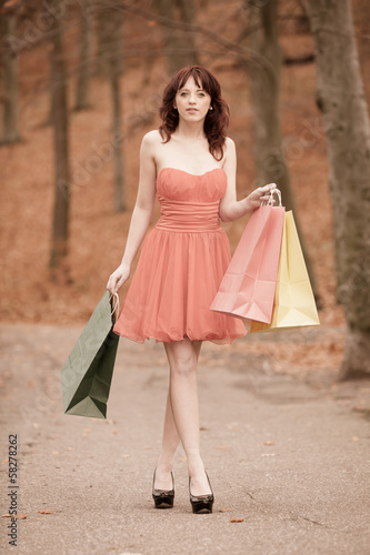 Elegant shopper woman walking in park after shopping