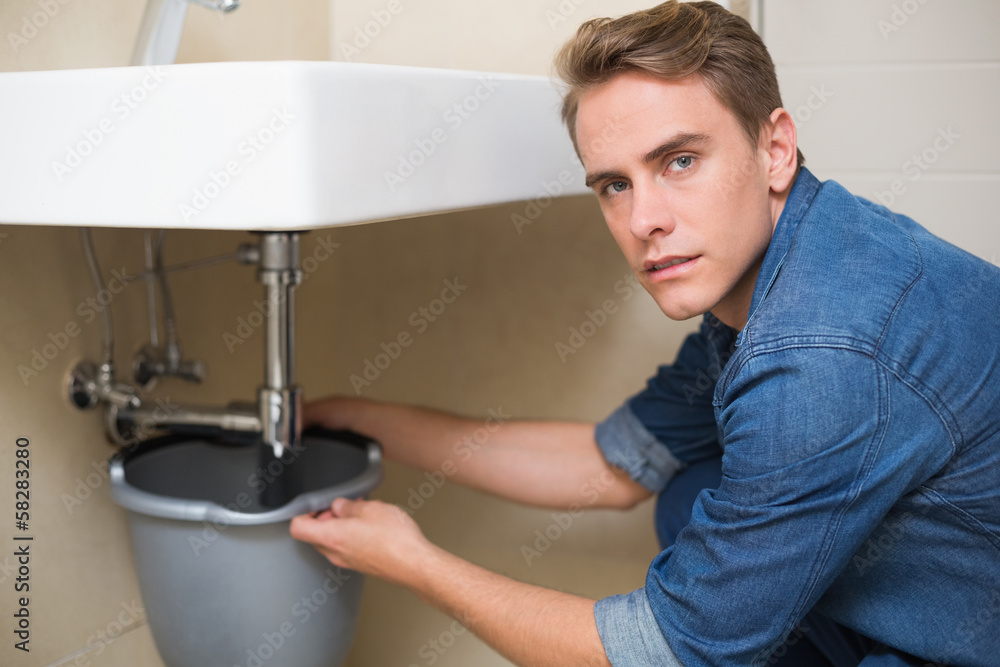 Handsome plumber repairing the drain of sink Handsome plumber repairing the drain of sink