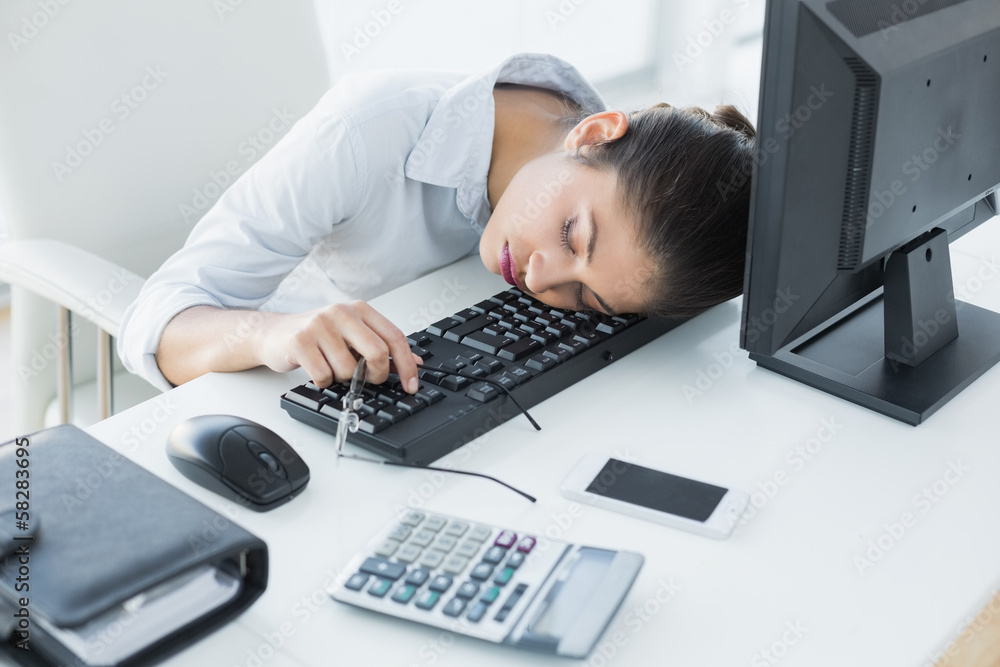 Businesswoman resting head on keyboard in office Businesswoman resting head on keyboard in office