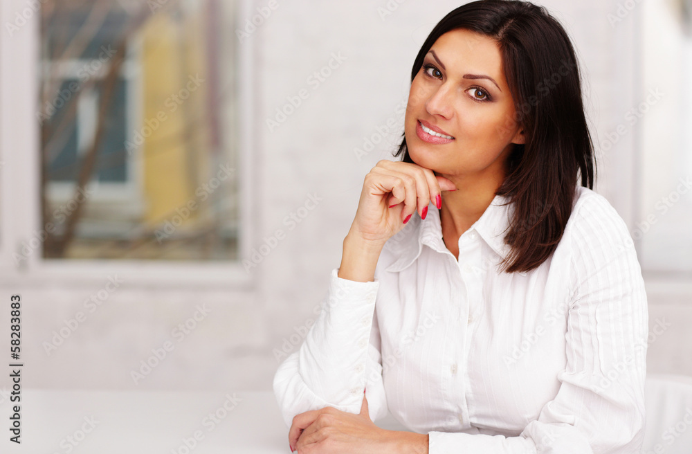 Happy confident businesswoman sitting at the table in office Happy confident businesswoman sitting at the table in office