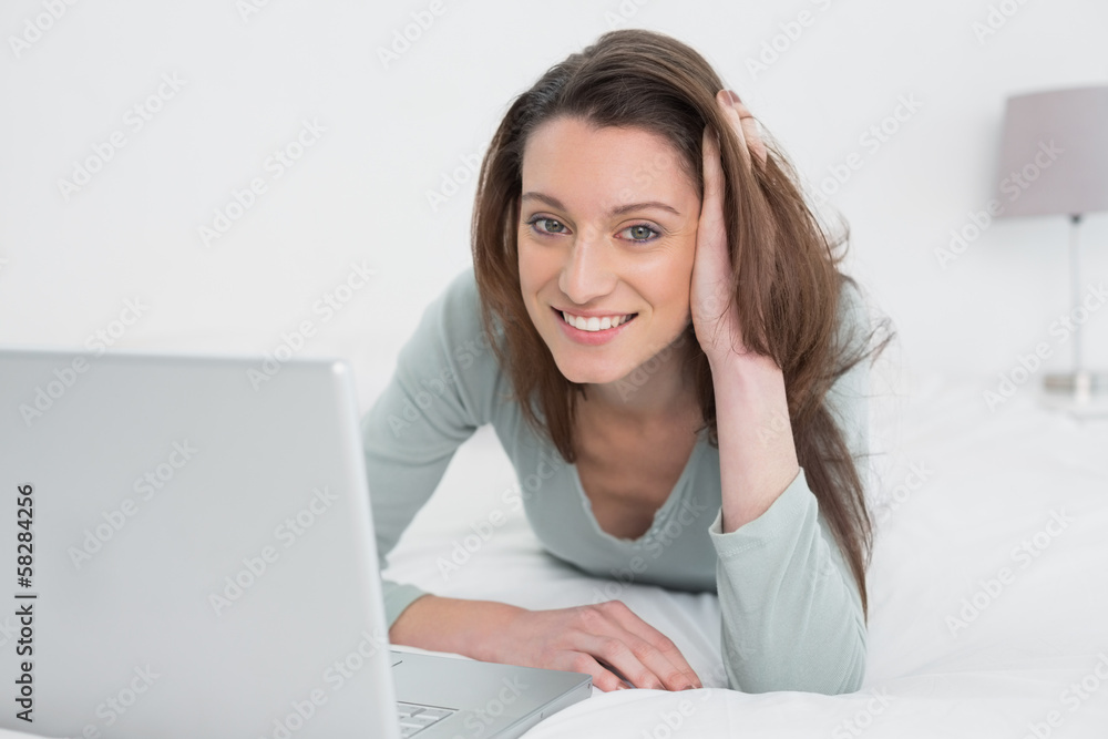 Relaxed casual smiling woman using laptop in bed Relaxed casual smiling woman using laptop in bed