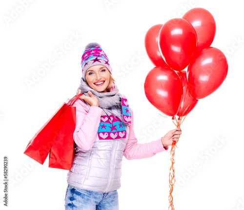 Smiling woman with gifts and red balloons after shopping