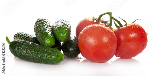 Three red tomatoes and heap of the cucumbers, isolated on white