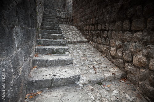 Old stone stairway goes up on the street of Perast town, Montene