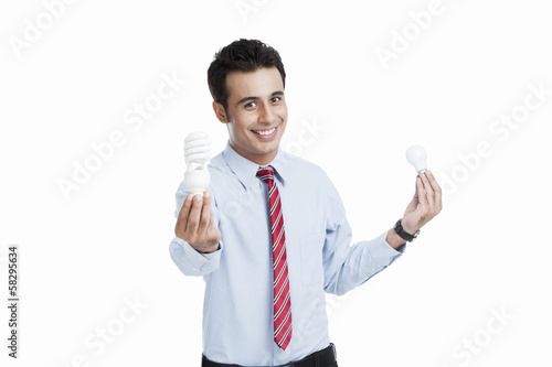Businessman comparing a light bulb with an energy efficient light bulb © imagedb.com