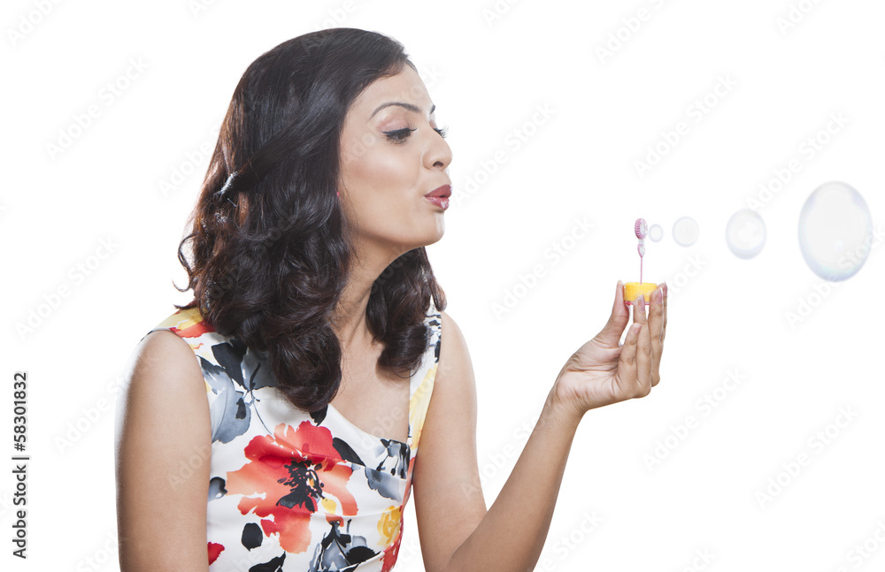 Young woman blowing bubbles with a bubble wand Young woman blowing bubbles with a bubble wand