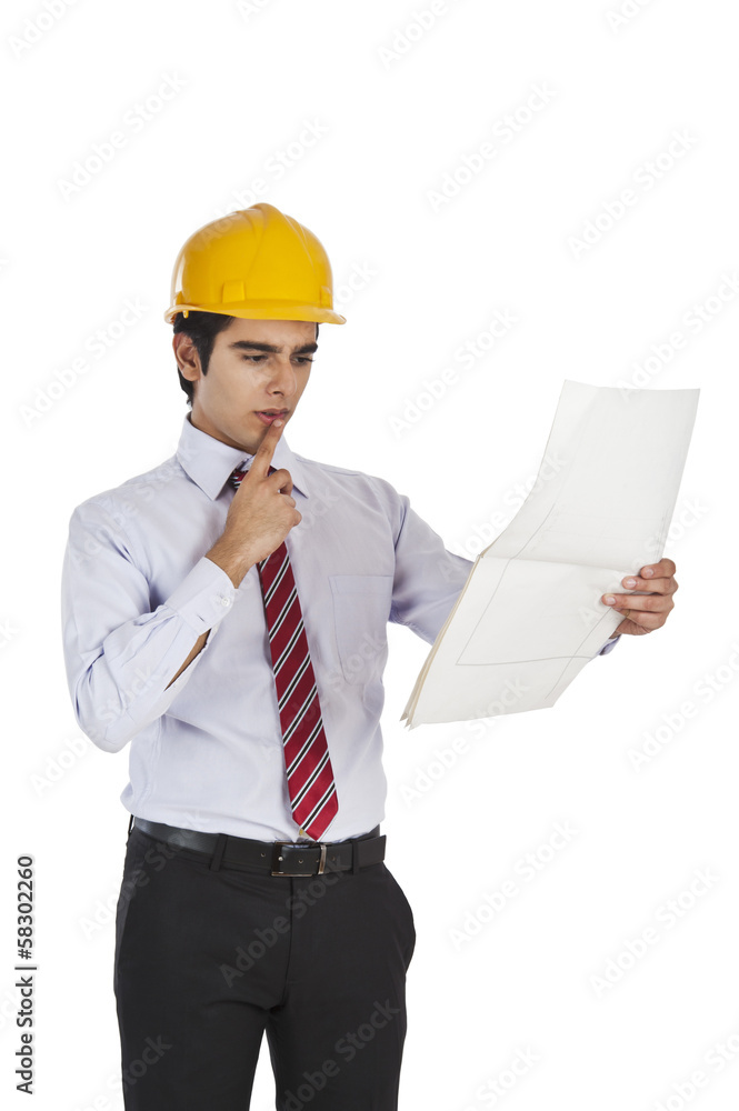 Male architect holding a blueprint and thinking Male architect holding a blueprint and thinking