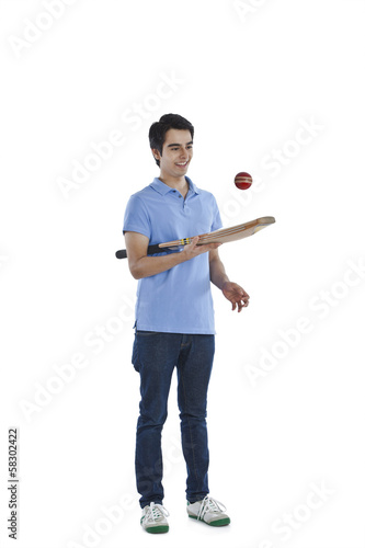 Man tossing a ball with a cricket bat © imagedb.com
