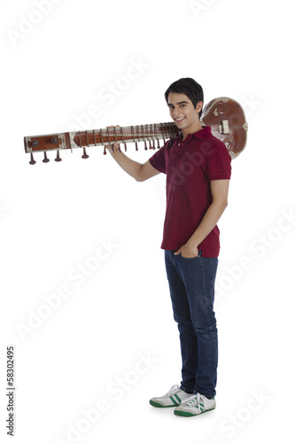 Man carrying a sitar on his shoulders and smiling