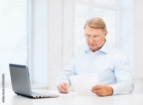 old man in eyeglasses filling a form at home