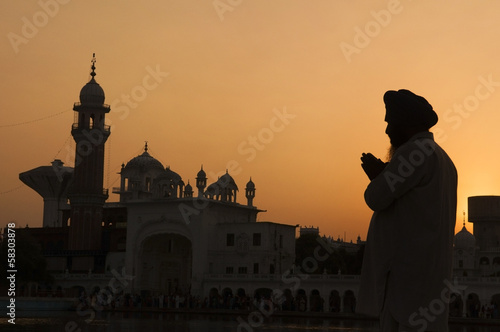 Silhouette of praying sikh man at golden temple of Amritsar, Ind