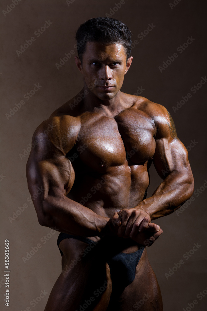 Fototapeta premium Young sports guy with a naked torso against a dark background