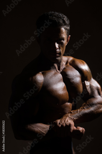 Strong athletic man on dark background © kanzefar