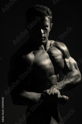 Young sports male with a naked torso against a dark background.