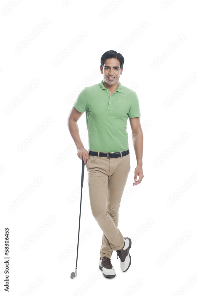 Male golfer standing with a golf club and smiling Male golfer standing with a golf club and smiling
