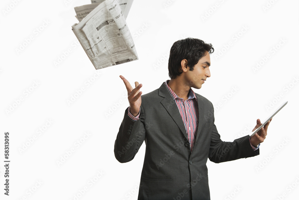 Businessman looking at a digital tablet and throwing newspaper Businessman looking at a digital tablet and throwing newspaper