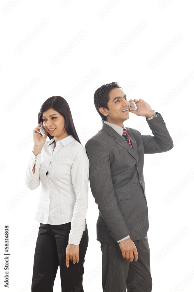 Two business executives talking on mobile phones Two business executives talking on mobile phones