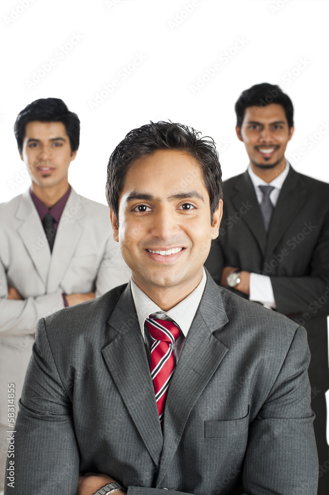 Portrait of a businessman smiling with his colleagues in the background Portrait of a businessman smiling with his colleagues in the background