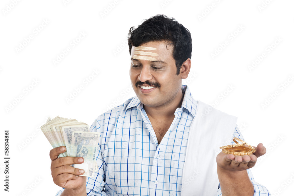 South Indian man holding money and gold bangle South Indian man holding money and gold bangle
