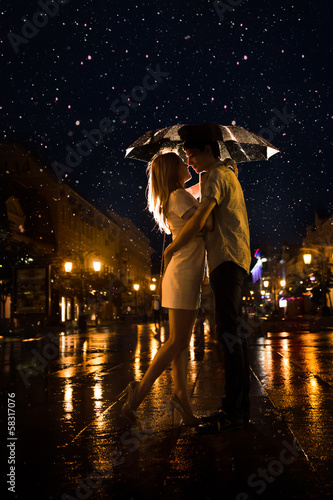 Love in the rain / Silhouette of kissing couple under umbrella