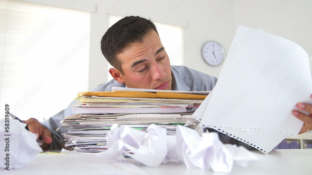 Overworked business man with large stack of papers