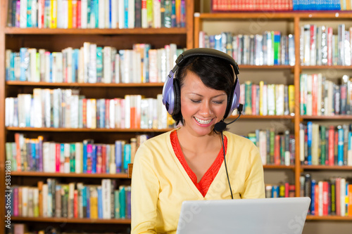 Young Girl in library with laptop and headphones