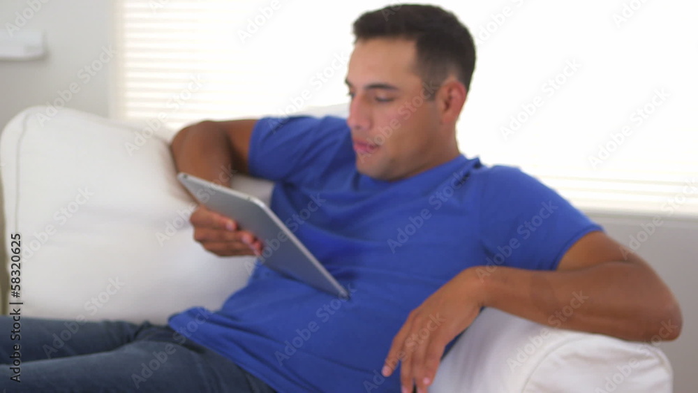 Pan up from pile of books to Hispanic man using tablet computer Pan up from pile of books to Hispanic man using tablet computer