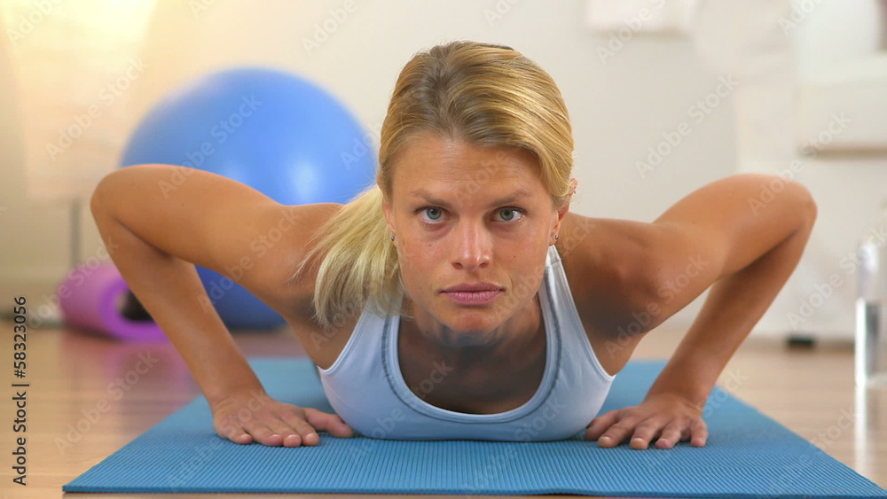Healthy woman doing push ups and looking at camera