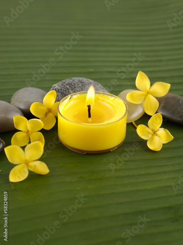 yellow flower and stones  candle on green banana leaf