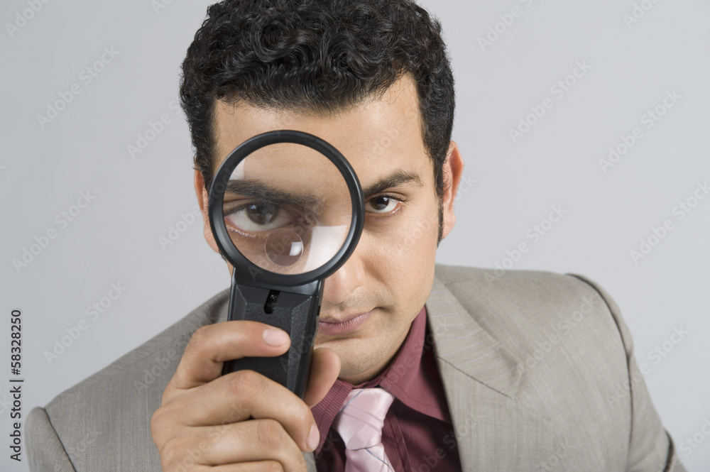 Businessman looking through a magnifying glass Businessman looking through a magnifying glass