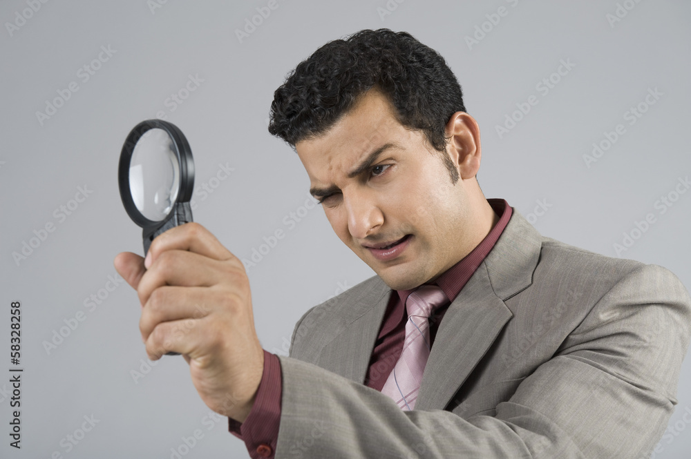 Businessman looking through a magnifying glass Businessman looking through a magnifying glass