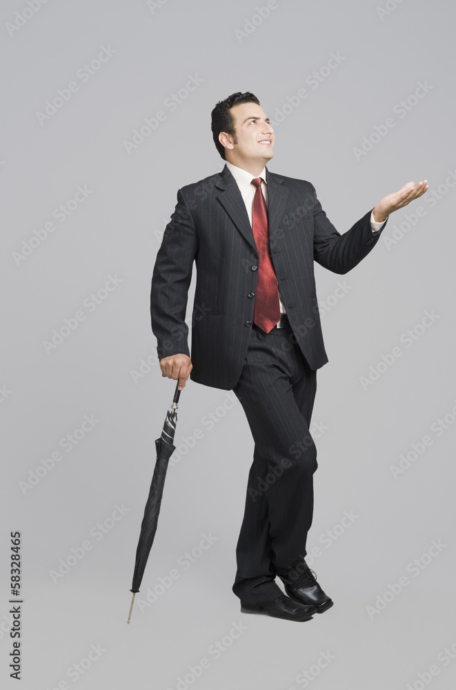 Businessman holding an umbrella and checking for rain
