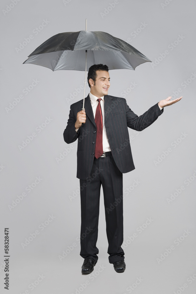 Businessman under an umbrella checking for rain Businessman under an umbrella checking for rain