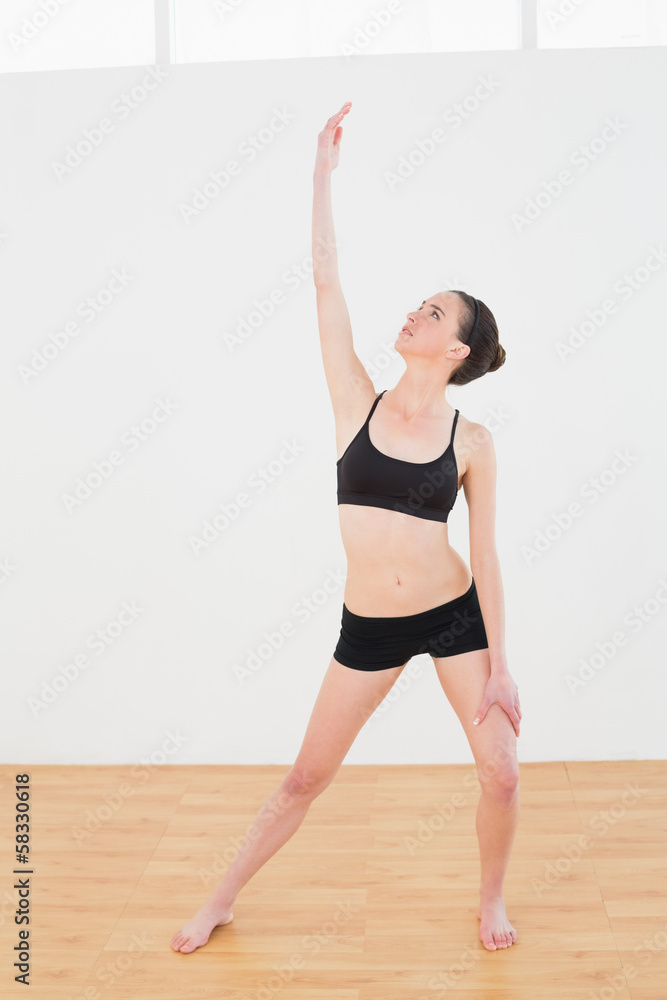 Naklejka premium Sporty woman stretching hand in fitness studio