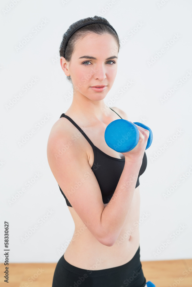 Serious fit woman exercising with dumbbell Serious fit woman exercising with dumbbell
