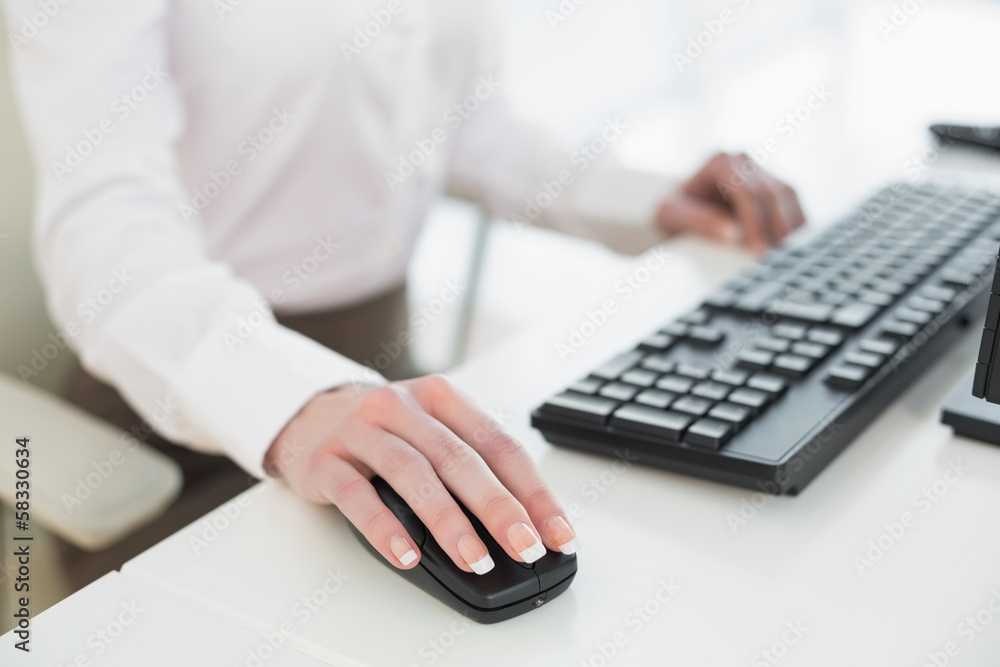 Mid section of businesswoman using mouse in office Mid section of businesswoman using mouse in office