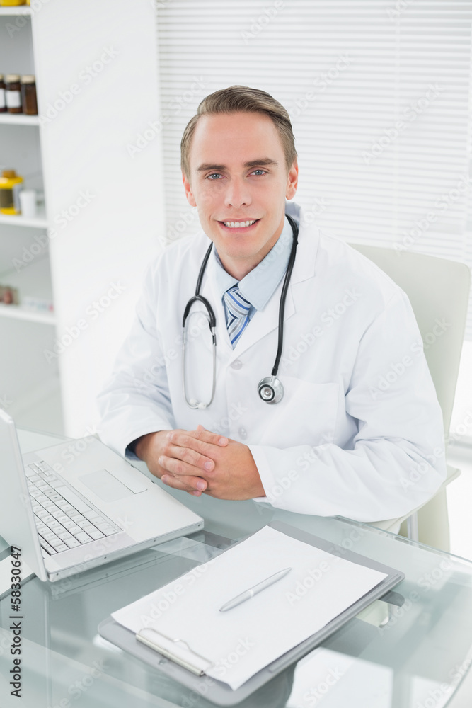 Smiling male doctor with laptop at medical office Smiling male doctor with laptop at medical office
