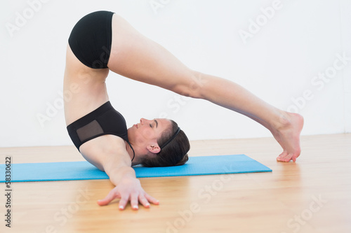 Fit woman doing the plough posture in fitness studio