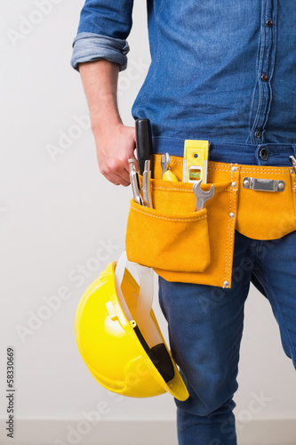 Mid section of a handyman with toolbelt and hard hat © lightwavemedia
