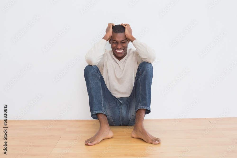 Angry casual Afro man sitting on floor against wall Angry casual Afro man sitting on floor against wall