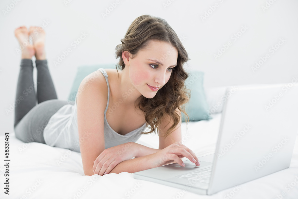 Relaxed casual brunette using laptop in bed Relaxed casual brunette using laptop in bed