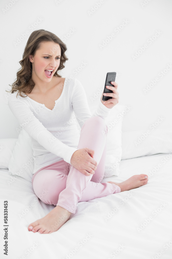 Cheerful woman looking at mobile phone in bed Cheerful woman looking at mobile phone in bed