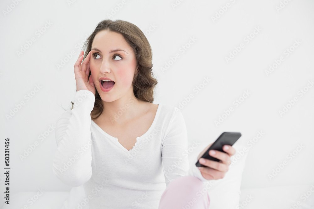 Shocked woman with mobile phone looking away Shocked woman with mobile phone looking away