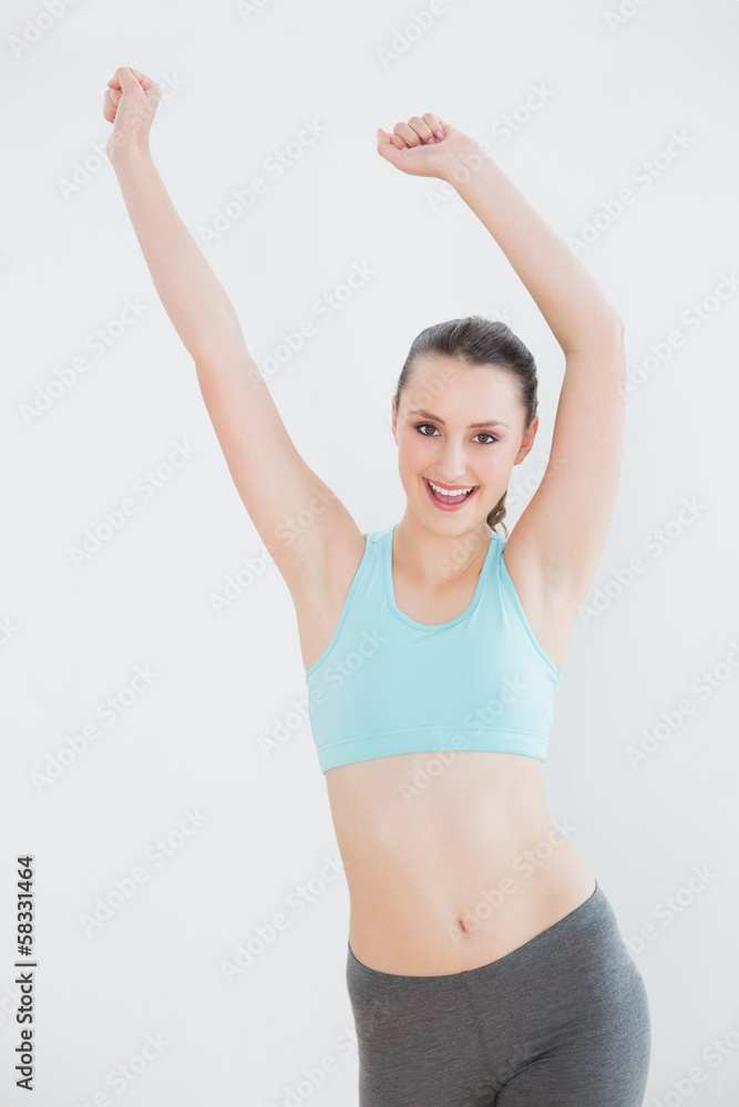 Smiling toned woman stretching hands against wall Smiling toned woman stretching hands against wall