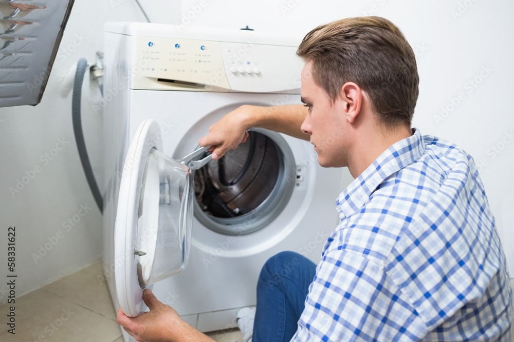 Technician repairing a washing machine Technician repairing a washing machine