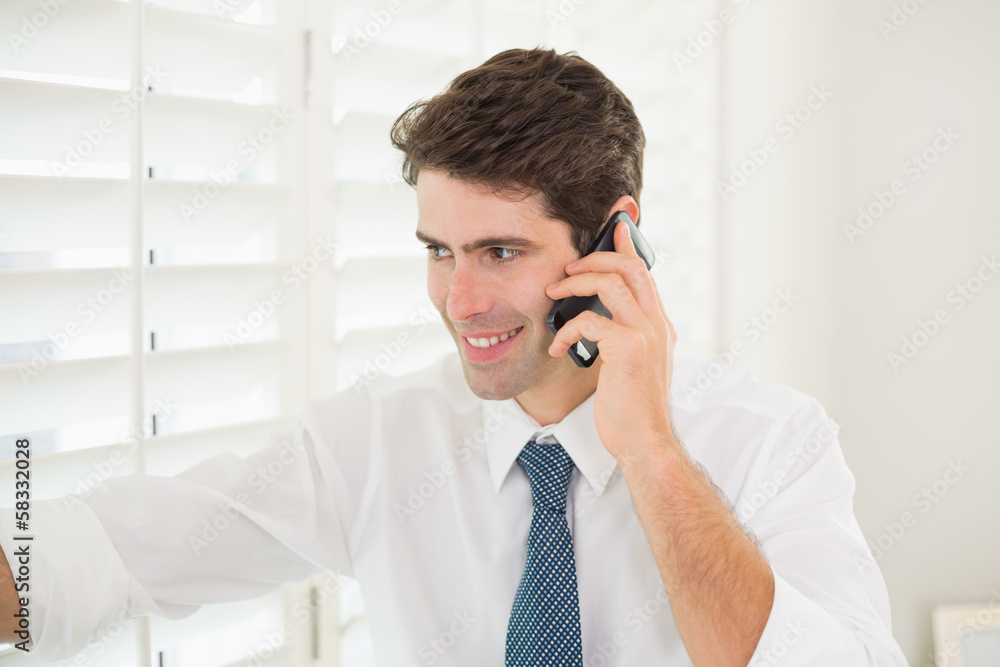 Businessman peeking through blinds while on call Businessman peeking through blinds while on call